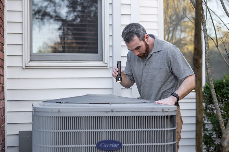 HVAC technician inspecting an outdoor AC unit at a Katy home